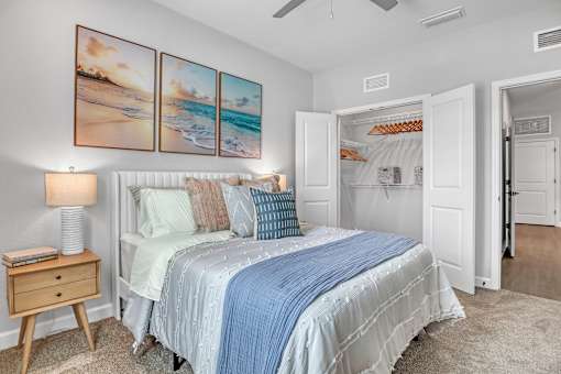 A bedroom with a bed, nightstand, and a painting of a beach scene on the wall.