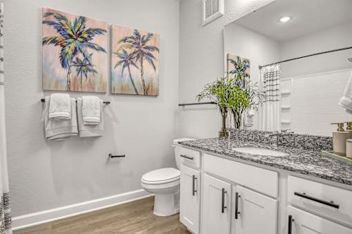 A bathroom with a toilet, sink, and two towels hanging on the wall.
