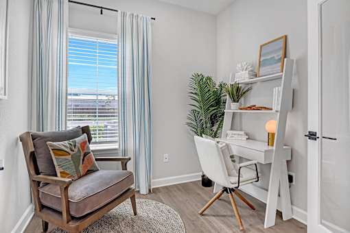 A room with a chair, a desk, and a plant.