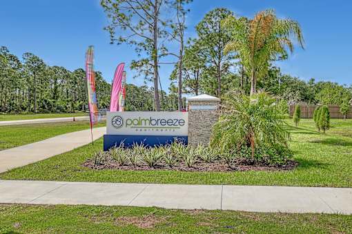 A sign for Palm Breeze Estates is in the foreground of a landscaped area.