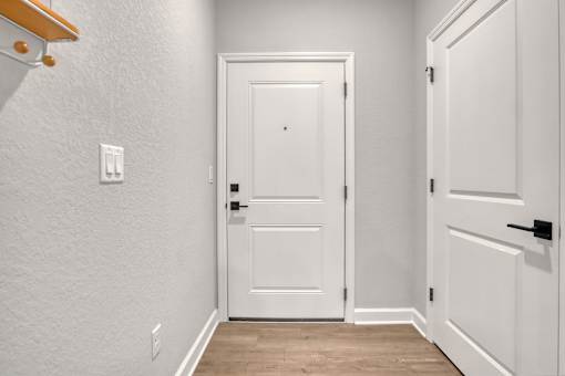 A white door is closed in a room with a light switch on the wall.