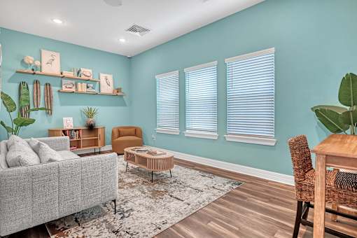 A living room with a grey couch, a wooden chair, a coffee table, and a rug.