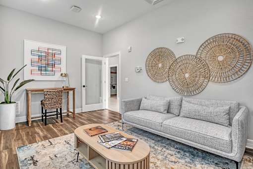A living room with a grey couch, a wooden table, and a painting on the wall.