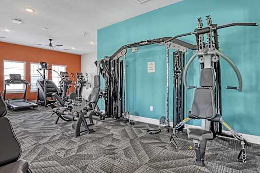A gym with a variety of equipment including treadmills, weights, and exercise machines.