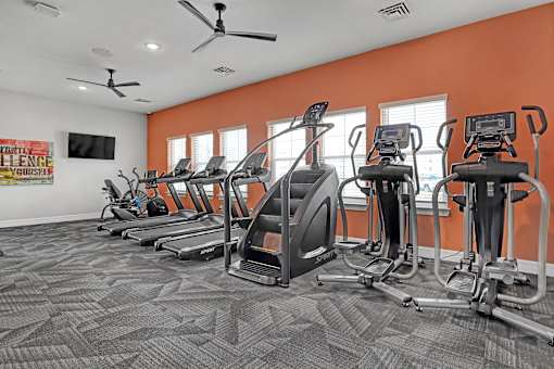 A gym with orange walls and a variety of exercise equipment.