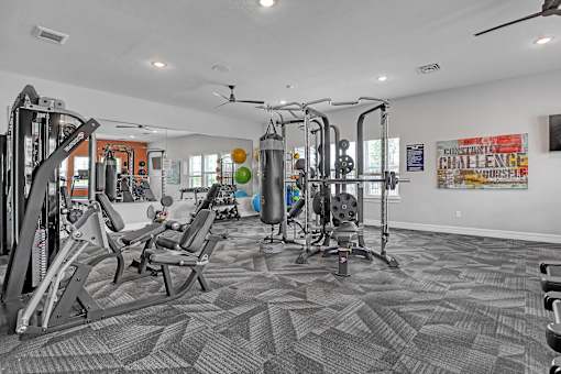 A gym with a variety of equipment including treadmills, weights, and a ceiling fan.