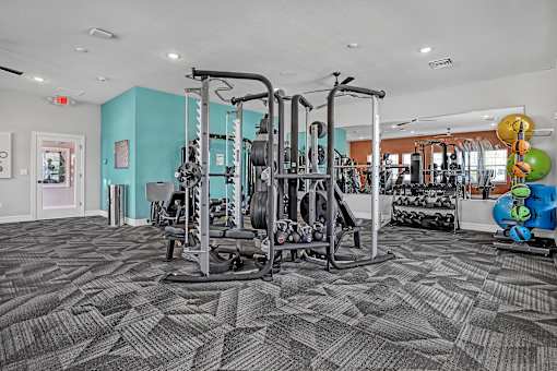 A gym with a variety of equipment including weights and machines.