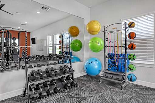 A gym with a variety of equipment including dumbbells, resistance bands, and exercise balls.