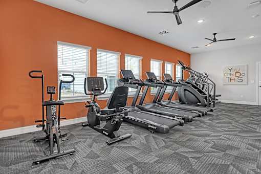 A gym with orange walls and a variety of exercise equipment.