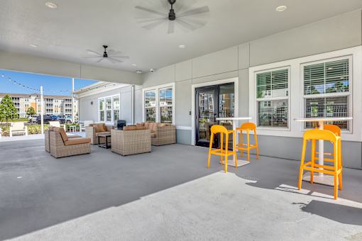 A patio with orange chairs and a ceiling fan.
