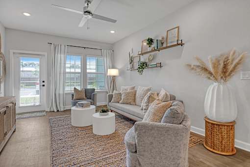 A living room with a grey couch, a white table, and a fan on the ceiling.