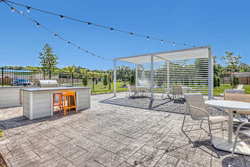 A patio with a table, chairs, and a barbecue grill.