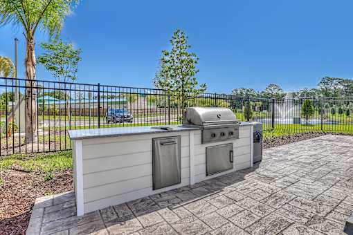 A white outdoor kitchen with a grill and sink.