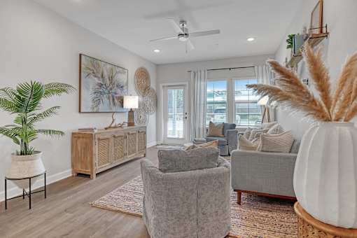 A living room with a grey couch, a wooden cabinet, a potted plant, and a painting on the wall.