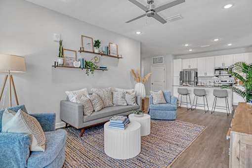 A living room with a grey couch, a white ottoman, and a wooden coffee table.