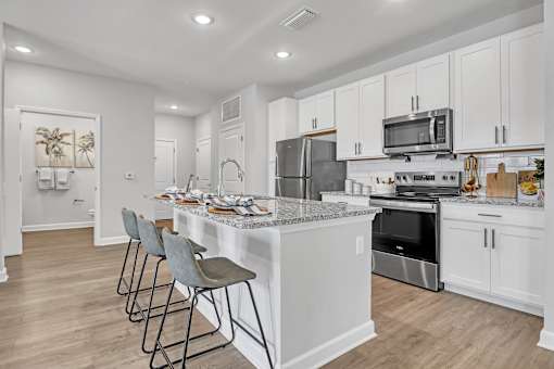 A kitchen with a white island and bar stools.