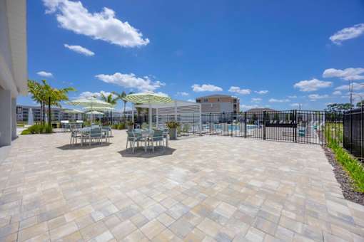 A patio with a table and chairs is surrounded by a black fence.