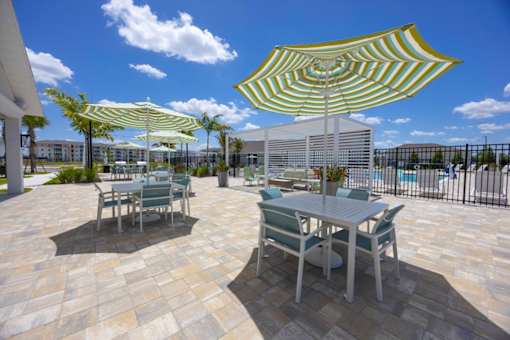 A patio with a table and chairs under a striped umbrella.