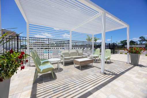 A patio with a white pergola and furniture.