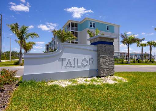 A white sign with the word "TAILOR" on it in front of a building.