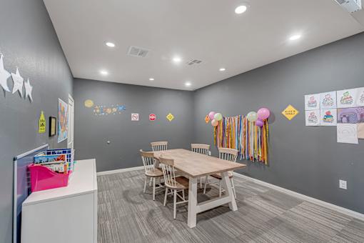 A room with a grey wall and a wooden table with chairs.