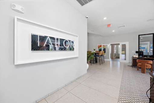 A hallway with a white wall and a framed picture with the word "AHOR" on it.