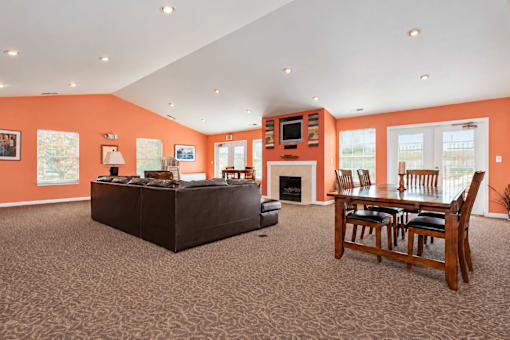 A living room with orange walls and a brown carpet.