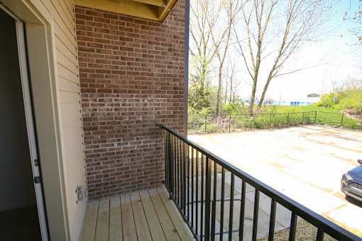 A balcony with a black railing and a brick wall.