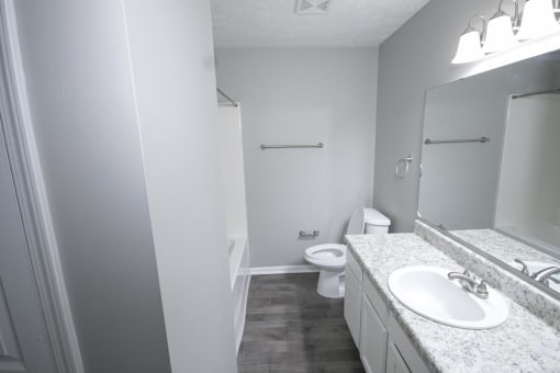 Bathroom with a sink toilet and mirror at Canterbury House apartments in Logansport, Indiana