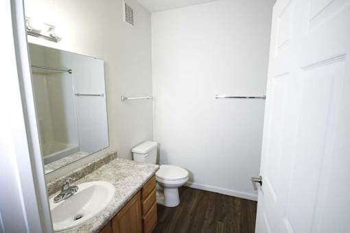 A white bathroom with a toilet, sink, and mirror.