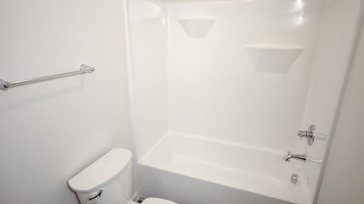 A white toilet sits next to a white bathtub in a bathroom.