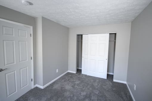 Bedroom with a closet and a door at Canterbury House apartments in Logansport, Indiana