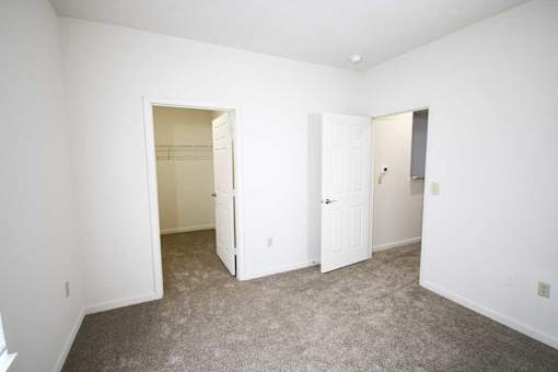 A white room with a carpeted floor and two open doors.