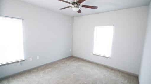 Empty bedroom with a ceiling fan and two windows at Mosaic Apartments in Avon, Indiana