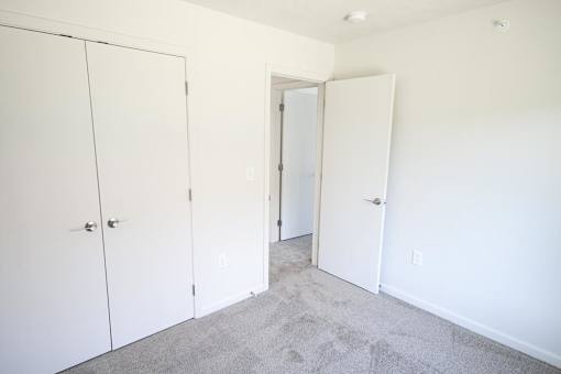 A room with white doors and carpeted floor.