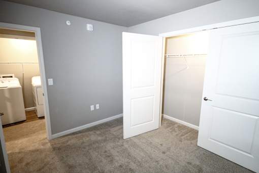 A room with a white door and a white wall with a light switch.