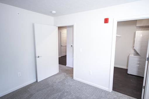 A room with a white door and a grey carpet.