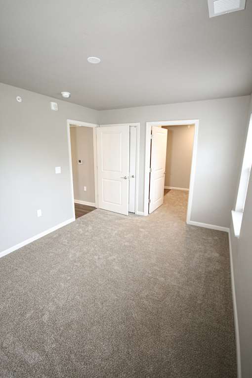 A room with a carpeted floor and two open doors.