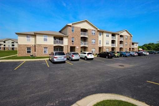 a parking lot with cars in front of Canterbury apartment buildings in Kalamazoo, Mi