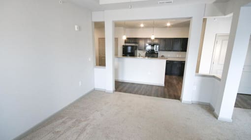 Empty living room with a kitchen in the background at Mosaic Apartments in Avon, Indiana