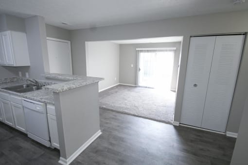 Kitchen and an empty living room with a door to a patio at Canterbury House apartments in Logansport, Indiana