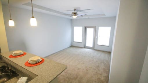 Living room view with a counter, ceiling fan, two windows and a door at Mosaic Apartments in Avon, Indiana