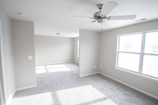 A room with a ceiling fan and a window letting in sunlight.