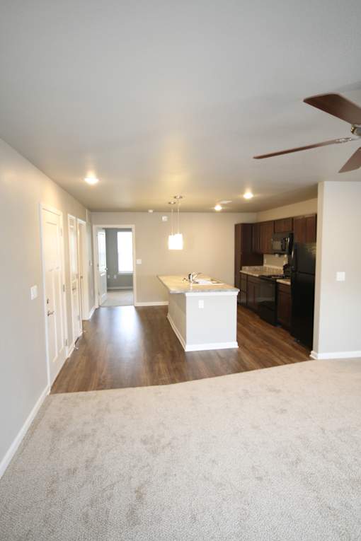 A spacious living room with a white ceiling fan and a white kitchen island.