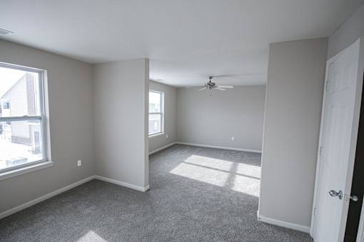 A room with a ceiling fan and a carpeted floor.