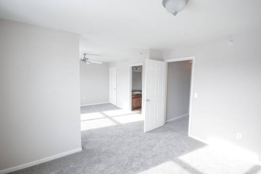 A white room with a carpeted floor and a doorway leading to another room.