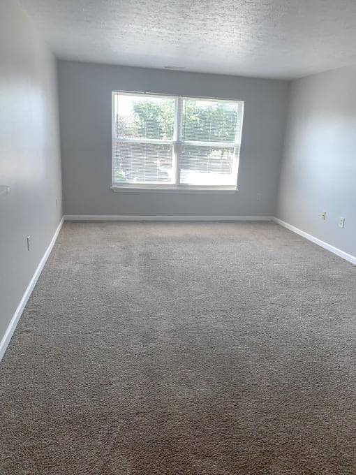 Empty living room with a window at Conner Court apartments in Connersville, IN