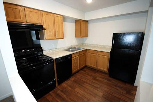 A kitchen with black appliances and wooden cabinets.