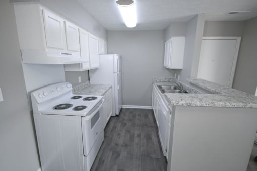Kitchen with a white stove, refrigerator and sink at Canterbury House apartments in Logansport, Indiana