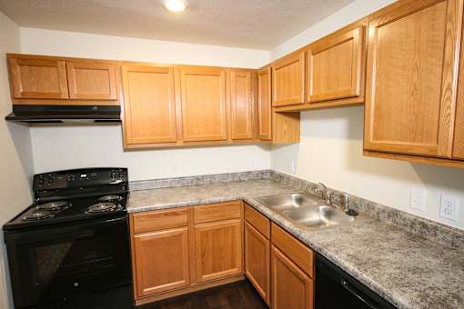 A kitchen with wooden cabinets and a black stove top oven.